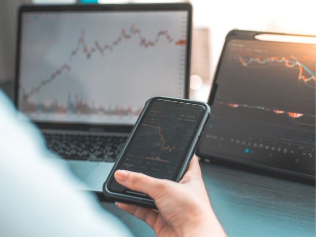 Trader analyzing market charts on a smartphone, laptop, and tablet, showcasing trading strategies with a clean and professional setup.