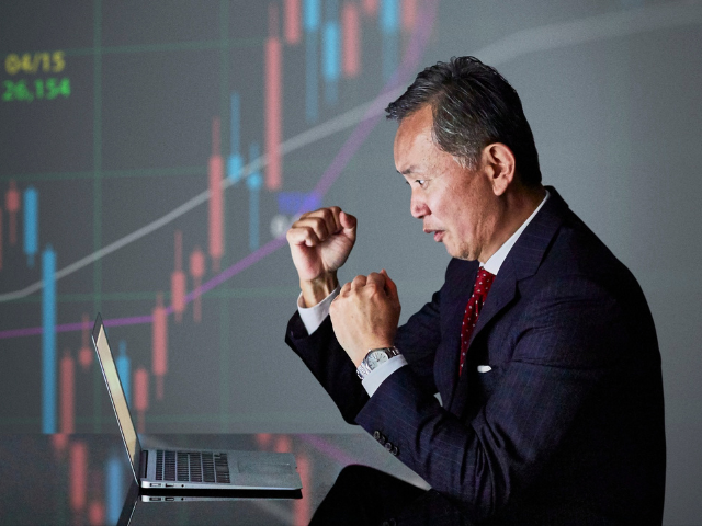 Man fighting a laptop with a trading chart in the background